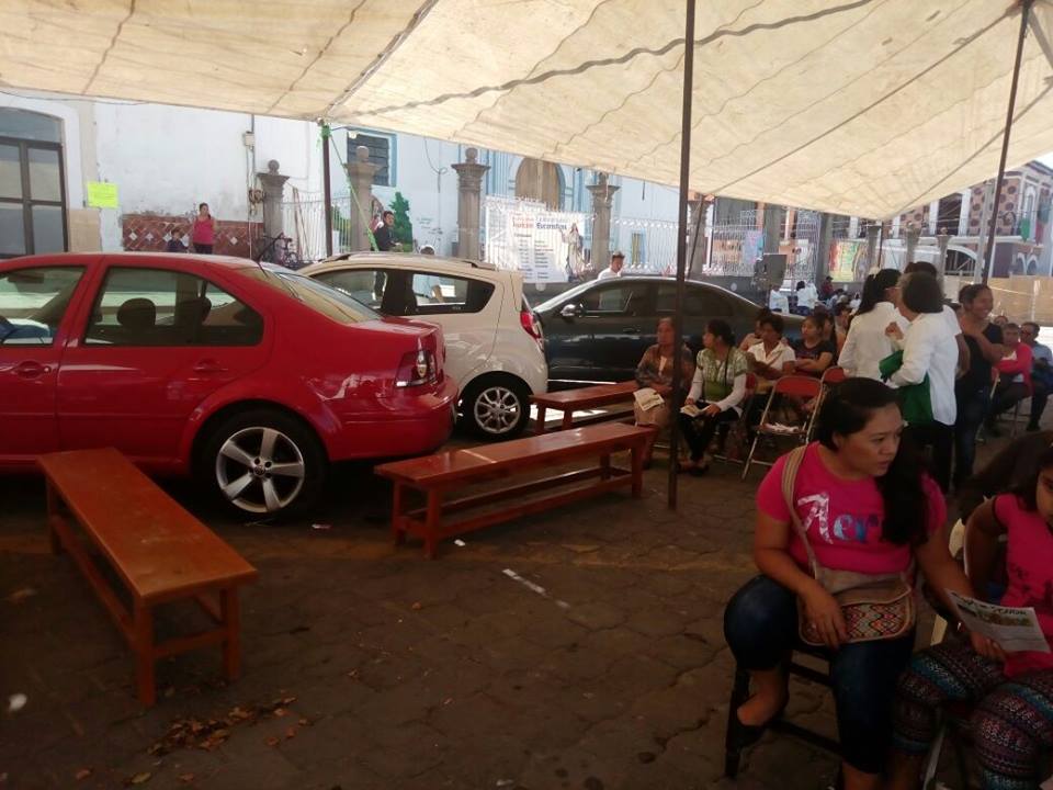 Feligreses escuchan misa en medio de estacionamiento en Izúcar