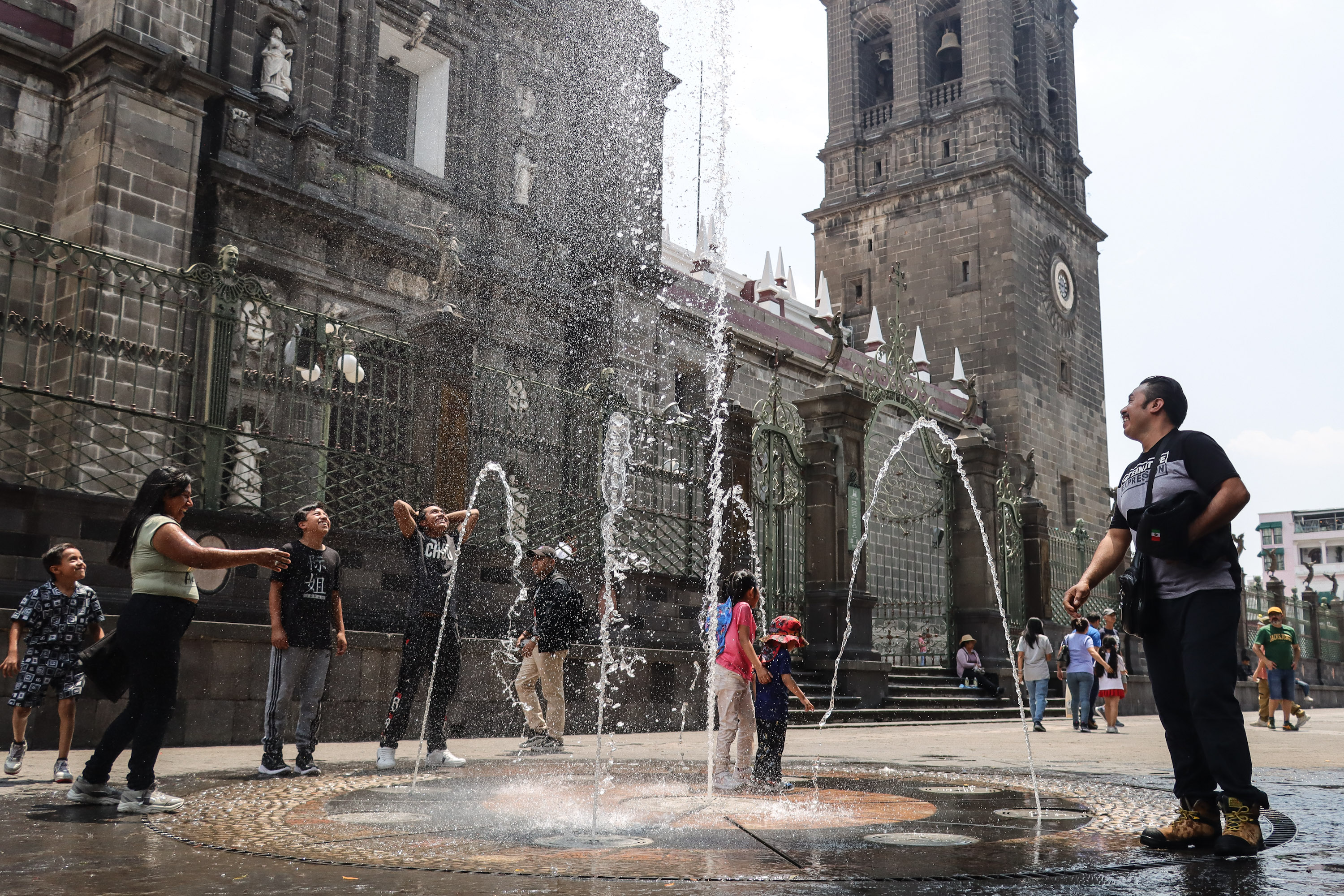 Poblanos calman el calor en fuentes del Zócalo
