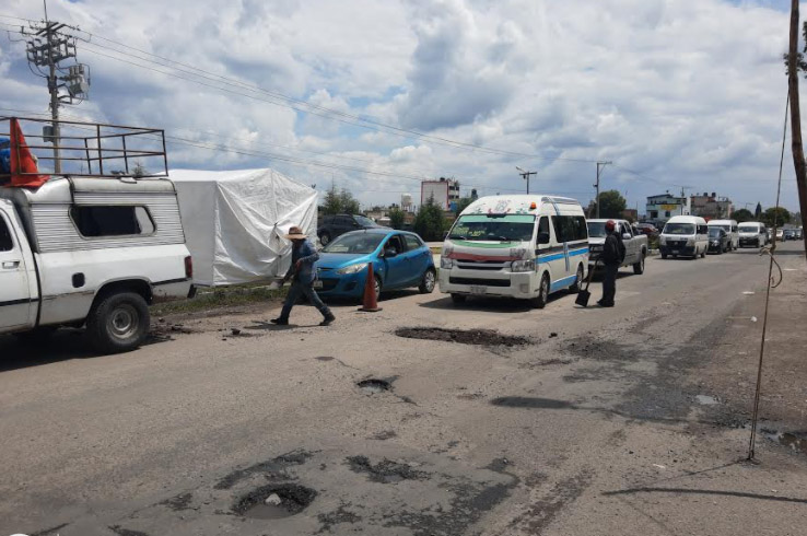 Vecinos realizan bacheo sobre vialidad de Texmelucan